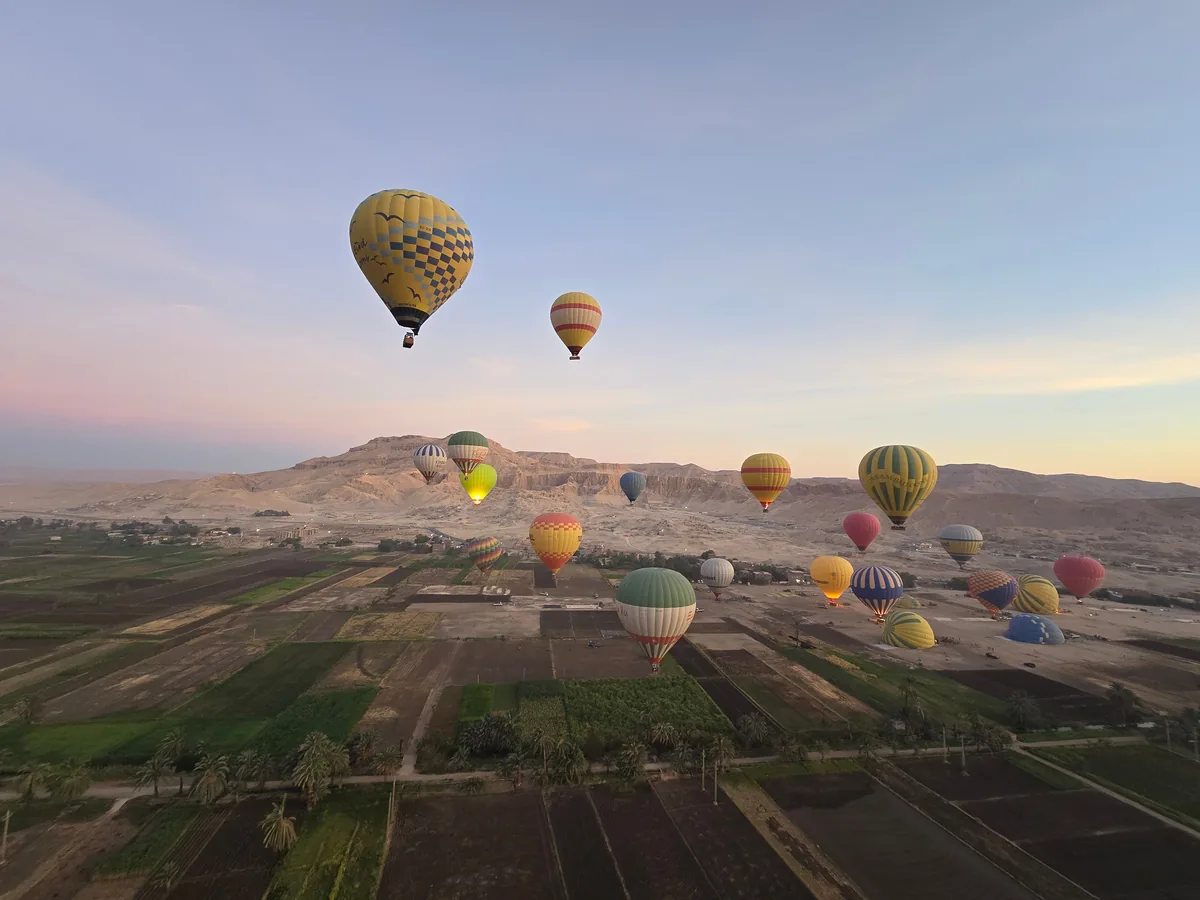 Hot-air balloons ascending over the Luxor desert landscape at dawn