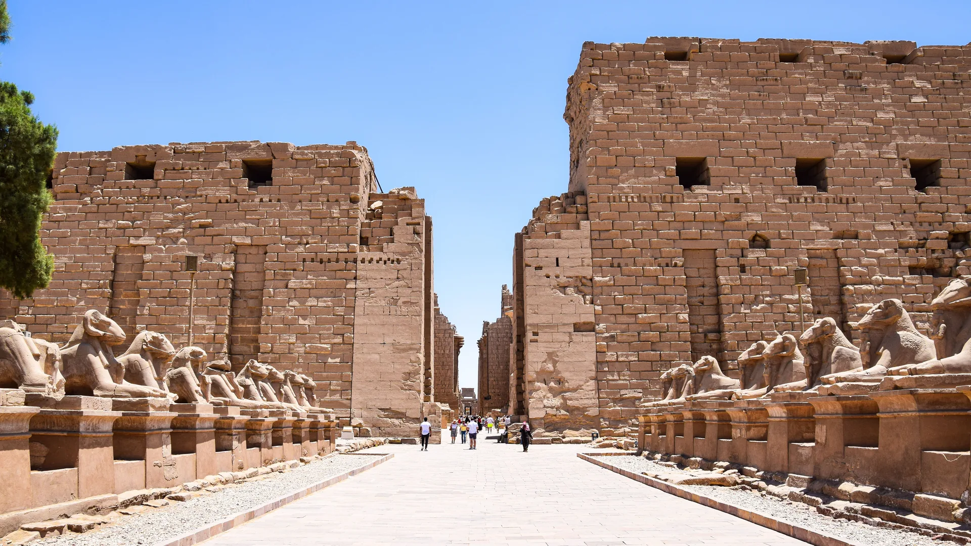 Karnak Temple's ancient sandstone columns and ruins under a bright blue sky in Luxor, Egypt